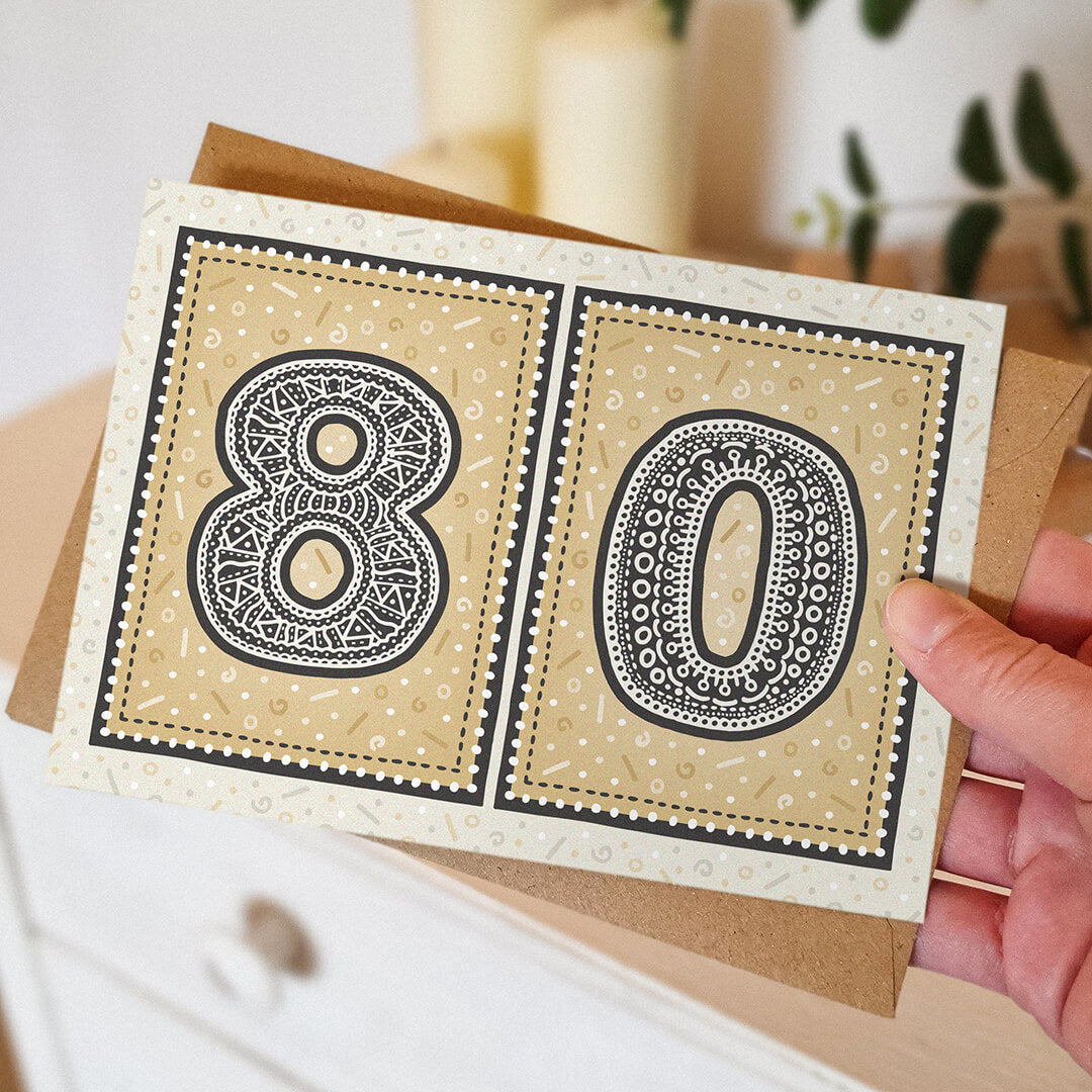 hand holding unique gold 80th birthday card with blurred background