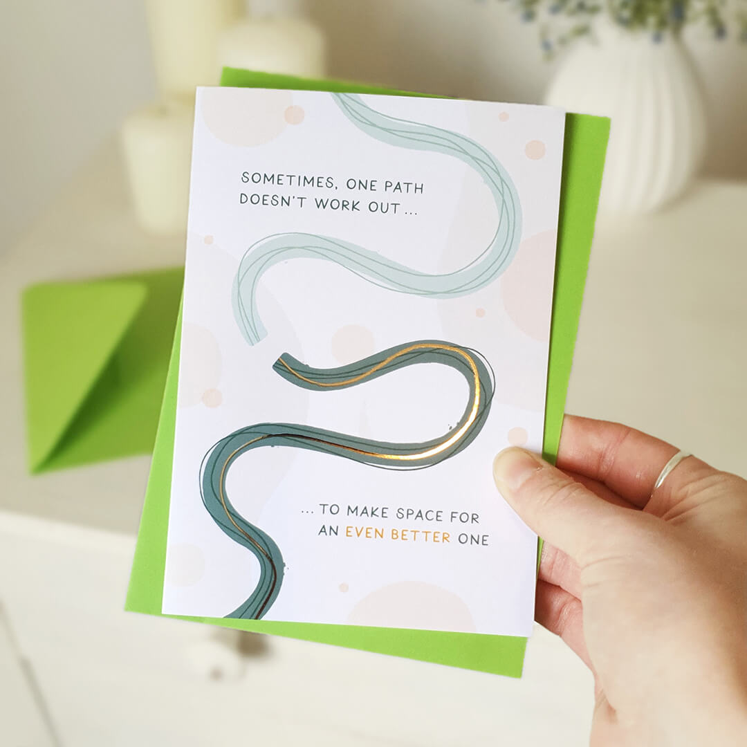 Hand holding a motivational card with a wavy line design and text on a light background