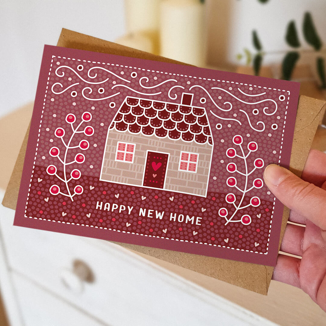Hand holding cute pink happy new home card Unique illustrated new home card featuring cute cottage illustration Printed on FSC-certified card and supplied with a kraft brown recycled envelope