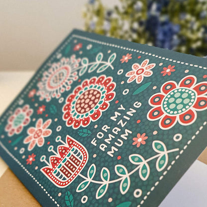 dark green and red mothers day card with floral and botanical illustrations in folk art style. Featuring 'for my amazing mum' message. Supplied with a recycled kraft brown envelope