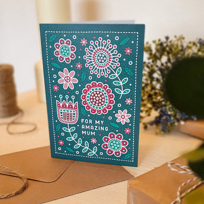 dark green and red floral mothers day card with folk art style floral illustrations and 'for my amazing mum' message. Supplied with a kraft brown recycled envelope.