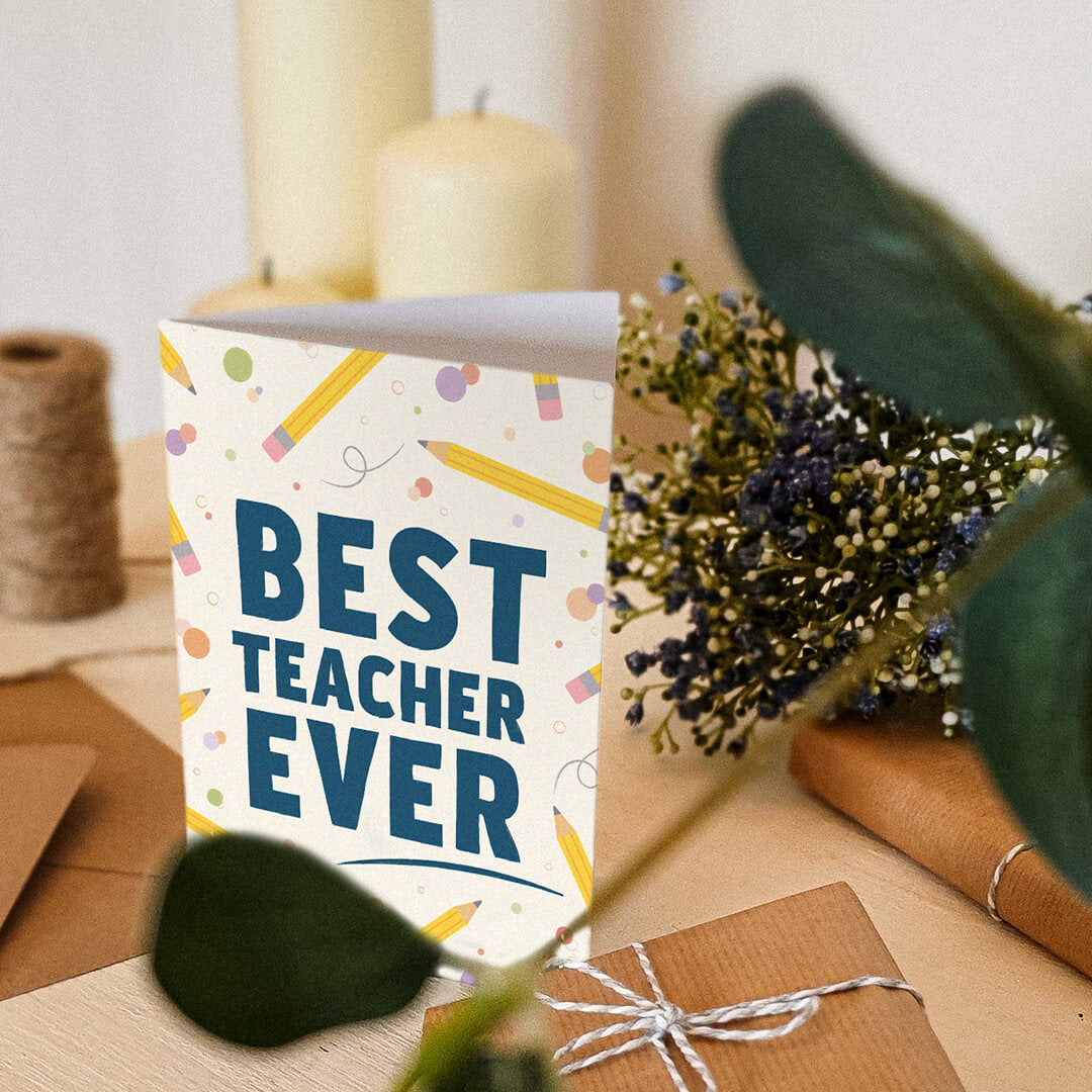 unique best teacher ever card sat on a cream wooden dresser surrounded by plants and candles