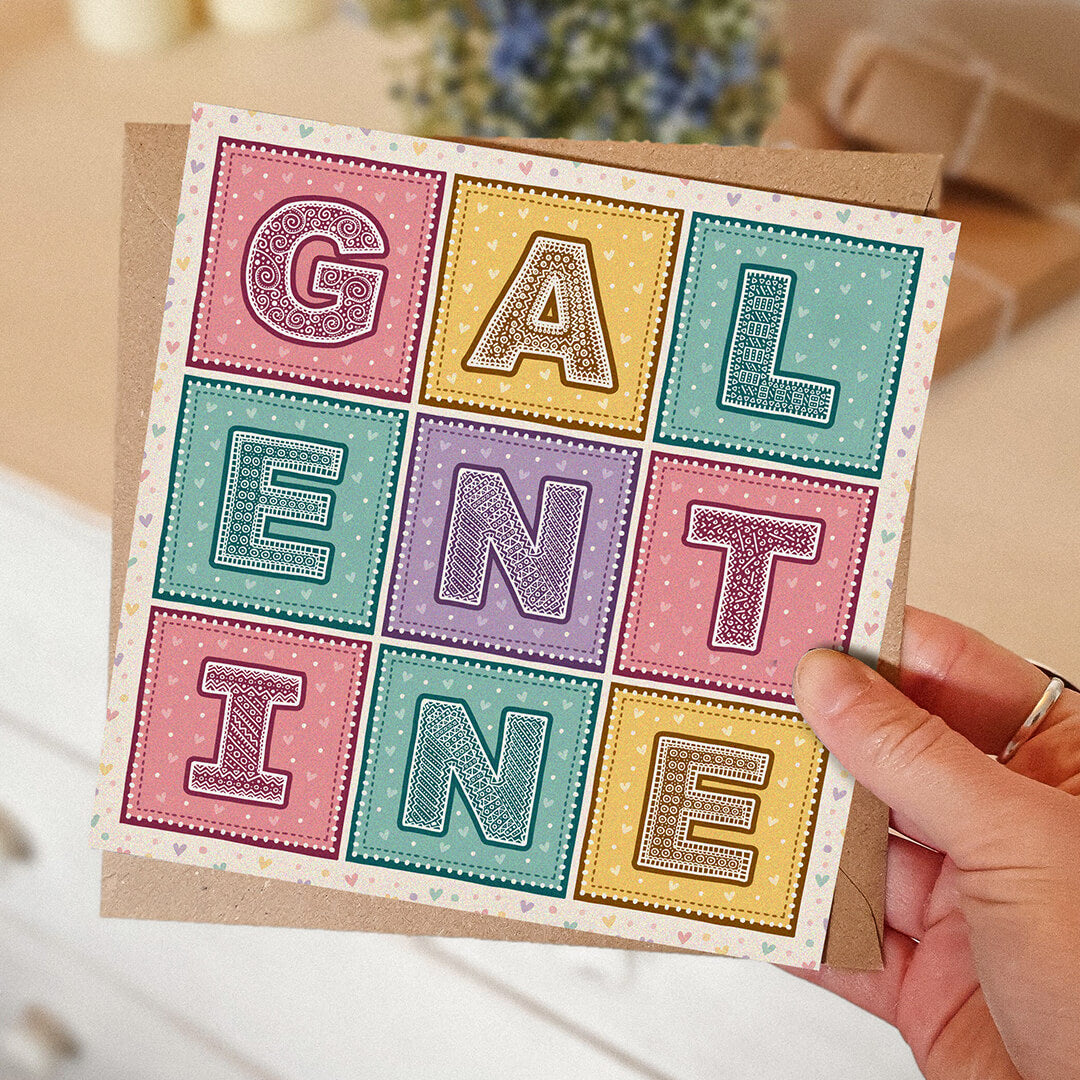 Hand holding cute pastel love hearts Galentine's Day card with blurred background