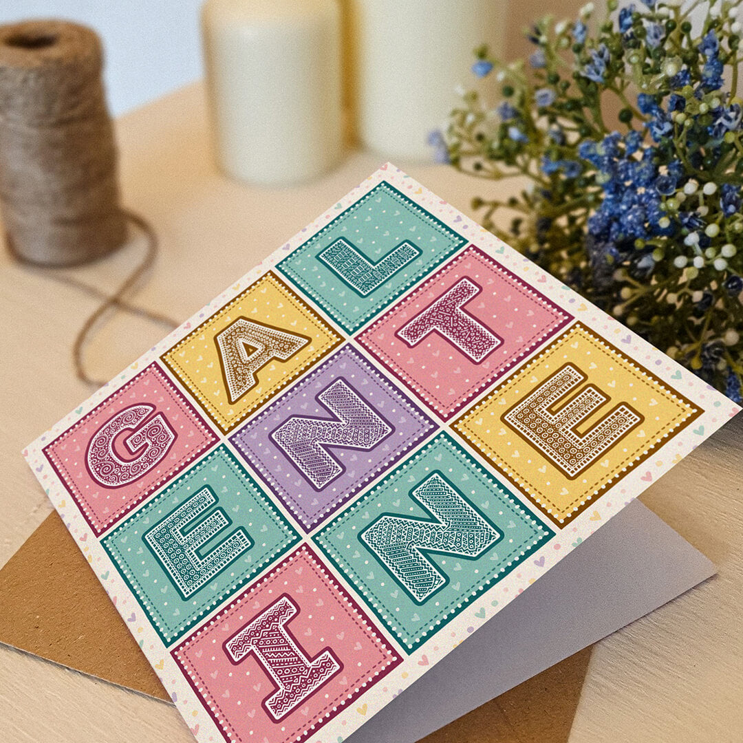 Pastel pink yellow turquoise and purple typographic Galentine's Day card with flowers and candles blurred in the background