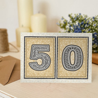 unique gold 50th birthday card with candles and flowers blurred in the background
