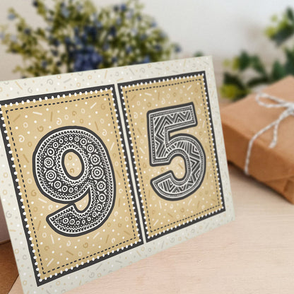 95th birthday card stood on a wooden surface with a blurred background