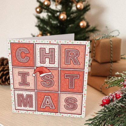 Red Christmas card with 'CHRISTMAS' text and a Santa hat illustration in front of a Christmas tree and presents.