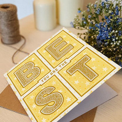 yellow starry thank you card with you are the best message led on a cream dresser with plants and candles in the background